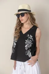 Blusa sin mangas de algodón color blanco con bordados florales negros en el frente y escote en V.