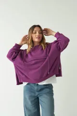 Buzo verde oscuro de corte recto y amplio, con capucha con cordones regulables y bolsillo frontal con cierre.