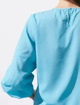 Blusa de gasa color blanco con estampado de hojas verdes, de mangas 3/4 abullonadas con puños elásticos.