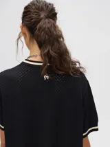 Vestido corto negro de tejido calado, con cuello redondo y mangas cortas con ribete en contraste.