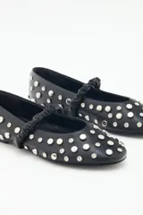 Ballerinas negras de cuero con tachas plateadas y tira elástica sobre el empeine.