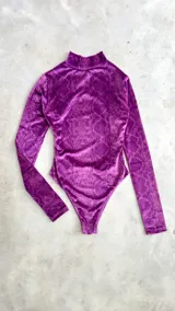 Body de terciopelo marrón con estampado de piel de serpiente, cuello alto, mangas largas con orificio para el pulgar y espalda descubierta.