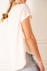Blusa color crudo de poliéster con mangas cortas y cuello redondo.