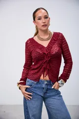 Blusa de manga larga color bordó, con tejido de punto calado, escote en V con volados y cierre frontal anudado.