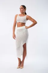Pollera midi de tejido calado color blanco, con cintura elástica y abertura lateral.