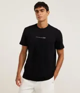 Remera negra de algodón, modelo comfort, con cuello redondo y manga corta. Presenta una pequeña estampa frontal en blanco con texto y un diseño minimalista de montañas.