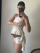 Short blanco de tiro alto con lentejuelas y cinturón marrón con tachas.