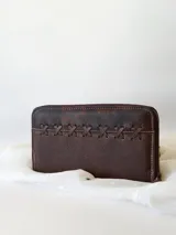 Billetera de cuero marrón con cierre metálico y diseño de cruces cosidas en el frente. Incluye monedero interno y espacio para billetes extendidos.