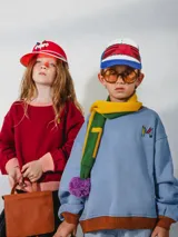 Bufanda azul y marrón con pompones grises, confeccionada en algodón.