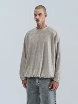 Sweater de tejido jaspeado color beige claro, con cuello redondo, mangas ranglán y elástico ajustable en el bajo.