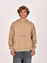 Hoodie color beige, con capucha y bolsillo canguro frontal. Presenta un estampado minimalista en el pecho con texto y un círculo.