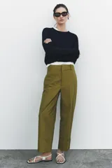 Pantalón color beige de corte ancho, con tiro medio, trabillas en la cintura y raya planchada.