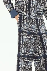 Pantalón de lino liviano con estampado paisley en tonos azul y blanco. Modelo de corte holgado con cintura elástica de tiro alto, bolsillos laterales discretos y piernas amplias.
