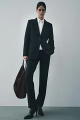 Blazer recta negra de Zara Woman Collection, con cuello solapa, manga larga con abertura y botones, bolsillos de plastrón en delantero, forro interior a tono y cierre frontal con botones.