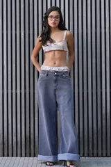 Conjunto de ropa interior de dos piezas, compuesto por un brasiere tipo crop top con breteles regulables y lazo en la espalda, y una pantie suelta fruncida con etiqueta de marca. El conjunto presenta un estampado con el nombre de la marca.