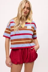 Remera tejida a rayas horizontales en tonos celeste, marrón y amarillo, con cuello polo amarillo y calce boxy.