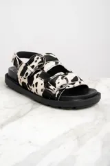 Sandalias con plataforma de goma negra y tiras de pelo de vaca con hebillas plateadas.