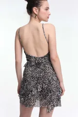 Vestido corto negro con lunares blancos, breteles finos y volados horizontales.