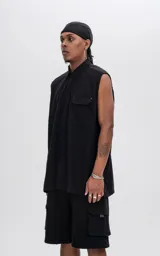 Camisa negra sin mangas de calce oversize con doble bolsillo y detalle de remaches en el frente, confeccionada en tejido twill de alta calidad.