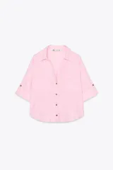 Camisa cropped color rosa de lino, con cuello solapa, escote pico, manga corta y bolsillos delanteros de plastrón.