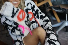 Sweater tejido a mano en 100% algodón, con diseño geométrico en blanco, negro, naranja y rosa. Corte holgado y flecos en el ruedo.