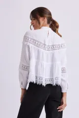 Blusa blanca de manga larga con cuello alto y detalles de encaje.
