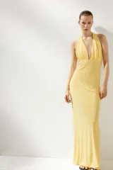Vestido largo amarillo con escote halter y espalda descubierta, atado al cuello.