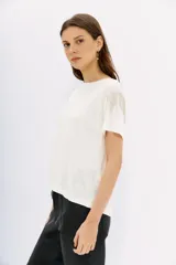 Remera blanca de lino con mangas cortas y calce al cuerpo. Presenta cadenas de strass en los hombros.