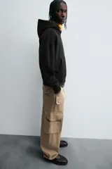 Pantalón cargo color beige, de corte relaxed fit, con bolsillos frontales, traseros con solapa y bolsillos laterales tipo parche con solapa.