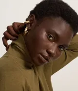 Blusa de punto color blanco, con cuello alto, manga larga y diseño liso.