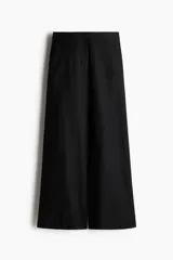 Pantalón negro de corte ancho, tiro alto, con bolsillos al bies y cierre oculto.