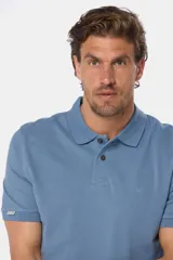 Remera polo azul de piqué liso, con cuello de rib y botones personalizados.