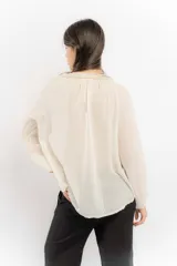 Blusa celeste de algodón con escote en V con lazos y mangas largas abullonadas con puños elásticos.