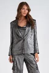 Blazer plateado de satén laminado, con cuello con solapa y abertura central con botón. Forro interno a tono.