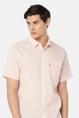 Camisa manga corta color rosa claro, con cuello clásico, cierre frontal con botones y bolsillo en el pecho.
