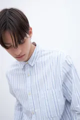 Camisa celeste con rayas verticales blancas, de corte regular, con cuello solapa clásico, bolsillo en el pecho y botones personalizados.