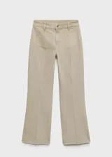 Pantalón de jean color beige, tiro medio, corte flare, con bolsillos de parche delanteros y ruedo desflecado.