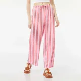 Pantalón ancho de punto gofrado color rosa con rayas verticales rojas y cintura con cordón ajustable.