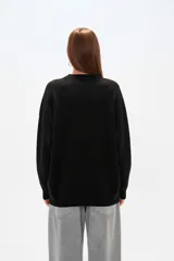 Sweater color crema, de corte holgado, con cuello redondo y mostacillas decorativas.