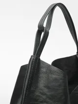 Bolso maxi hobo negro de piel bovina, con cantos al taglio, puntadas gruesas, un compartimento, cierre con nudo, asa de hombro y logo grabado.
