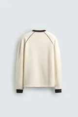 Sudadera color crema de corte relaxed fit, con cuello redondo y manga larga. Presenta un estampado en el frente con la palabra "ULTRAVEX" en letras negras y la palabra "FUTURIO" debajo.