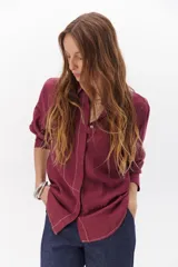 Camisa negra de manga larga con cuello clásico y cierre frontal con botones. Presenta costuras decorativas en color blanco.
