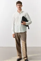 Camisa blanca de manga larga en mezcla de lyocell y algodón. Corte estándar, cuello inglés, tapeta clásica, bolsillo superior abierto, canesú con pliegue de caja en la espalda y bajo redondeado.