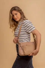 Bandolera de diseño moderno, color beige rosado, con correa regulable y bolsillo frontal con cierre.