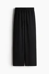 Pantalón negro de corte holgado y tiro alto, confeccionado en mezcla de lino. Presenta cintura elástica con cordón ajustable y piernas rectas.