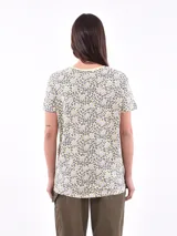 Remera blanca con estampado de flores y hojas en tonos pastel.