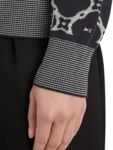 Sweater azul marino con diseño de rombos blancos con el logo de la marca en el centro. Tiene cuello redondo, puños y bajo acanalados.