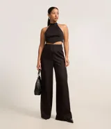 Pantalón de vestir negro de corte recto, sin cintura, con pinzas delanteras y cierre con cremallera y gancho.