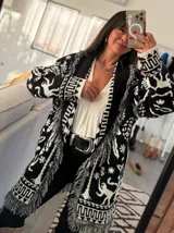 Sacón con estampado selvático en blanco y negro, tejido grueso tipo mohair y flecos artesanales. Incluye cinturón para ajustar la silueta.