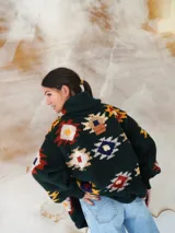 Saco de lana marrón con diseño geométrico multicolor, cuello con solapa, cierre frontal con botones y bolsillos delanteros.